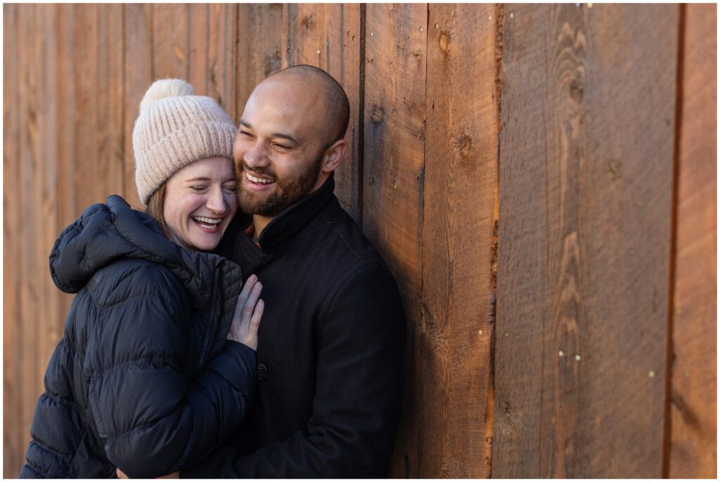 Couple laughing leaning on fence in downtown Breckenridge after their  proposal