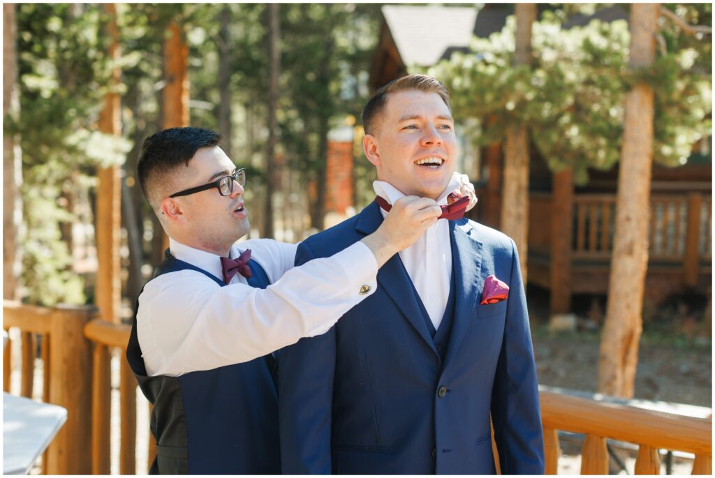 Groomsman helping groom put on tie