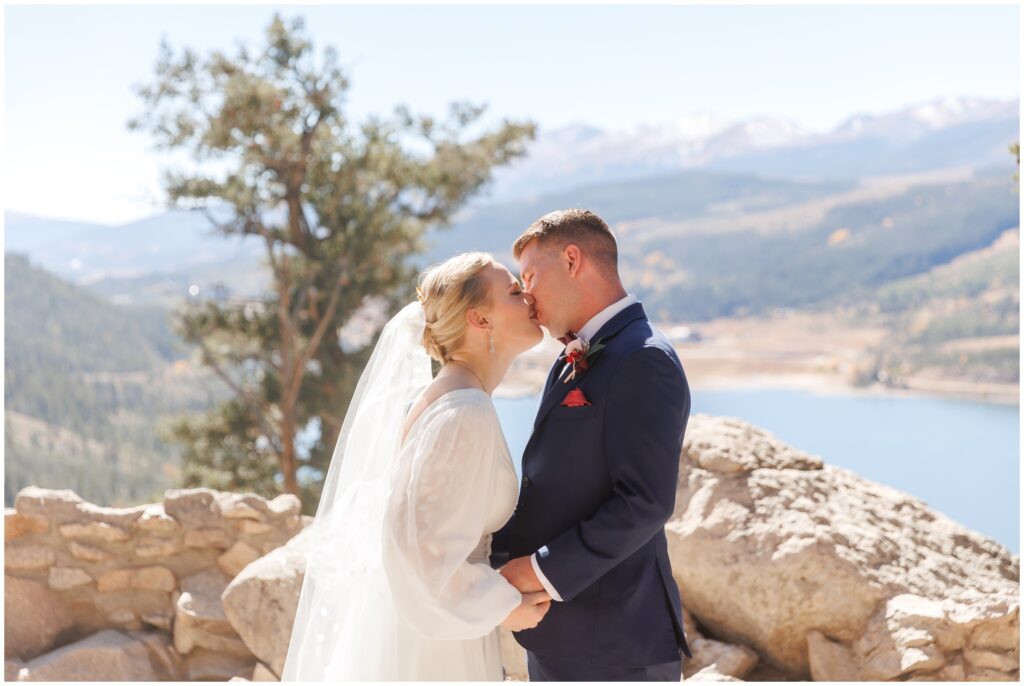 Bride and groom kissing during first look overlooking lake