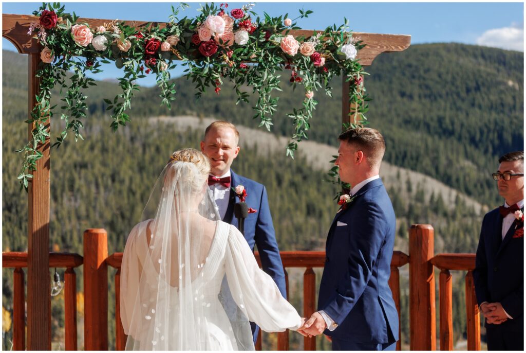 Bride and groom holding hands looking at officiant