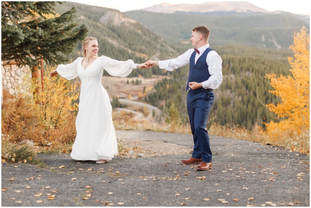 Bride and groom holding hands with fall leaves at The Lodge at Breckenridge