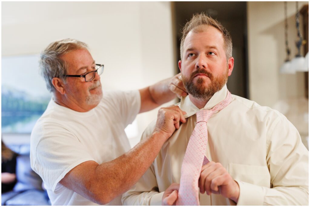 Groom putting on tie and getting ready for wedding