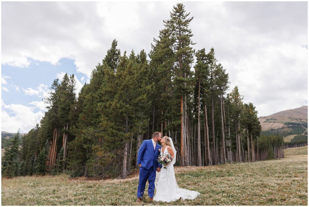 Bride and groom standing in front of pine trees in Breckenride