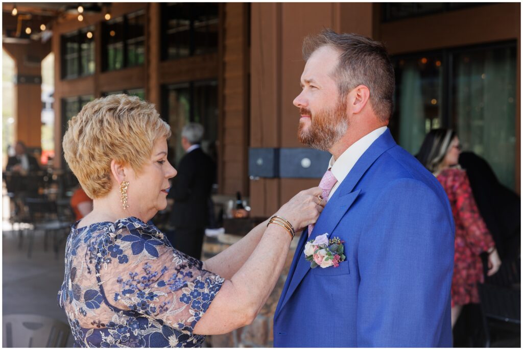 Mom adjusting tie for son before wedding