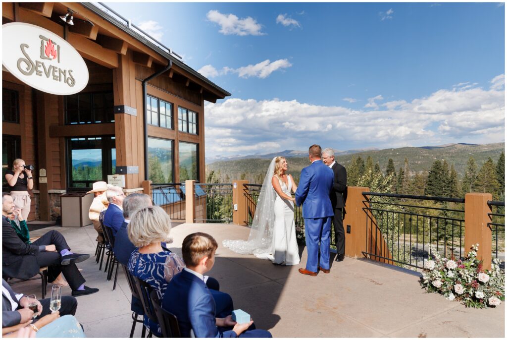 Bride and groom holding hands with officiant speaking to everyone at Sevens at Peak 7 in Breckenridge