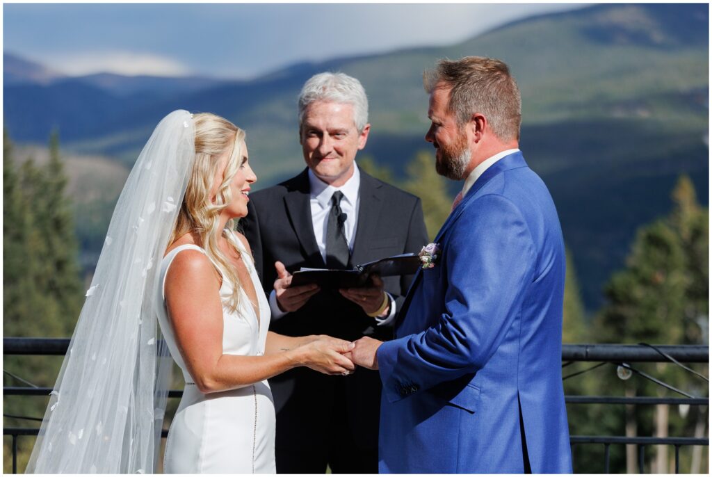 Officiant smiling with groom listing to bride speak