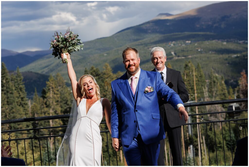 Bride celebrating with bouquet up in the air after ceremony