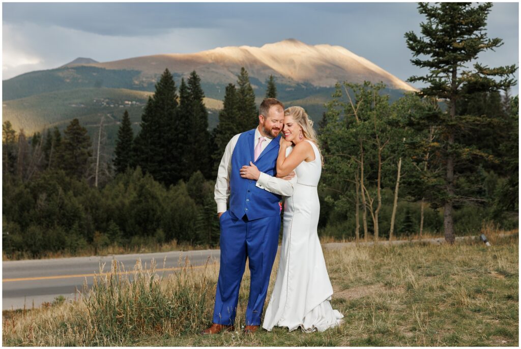 Bride and groom holding arms on grassy hill in Breckenridge