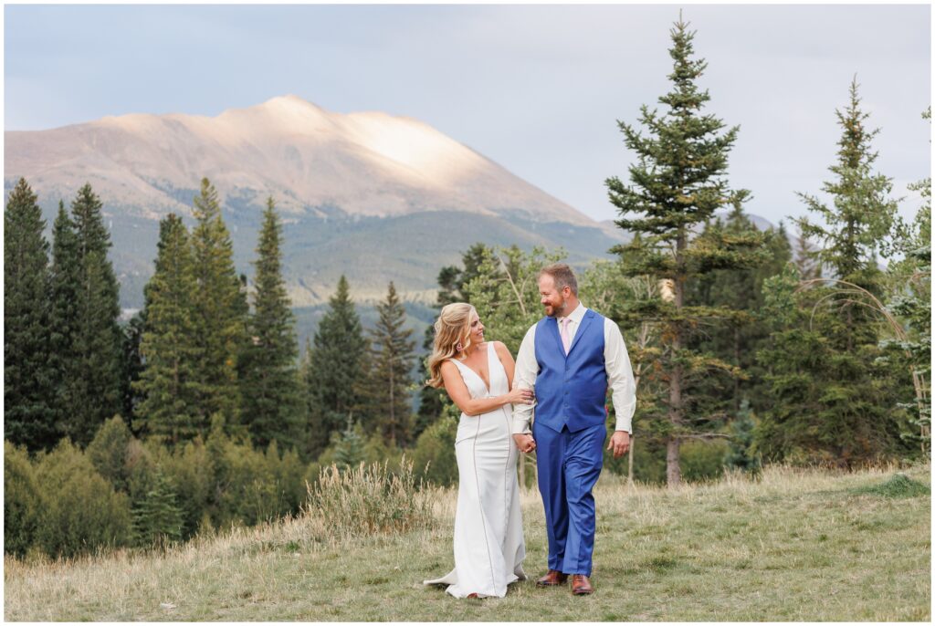 Bride and groom holding hands and walking down hill in Breckenridge