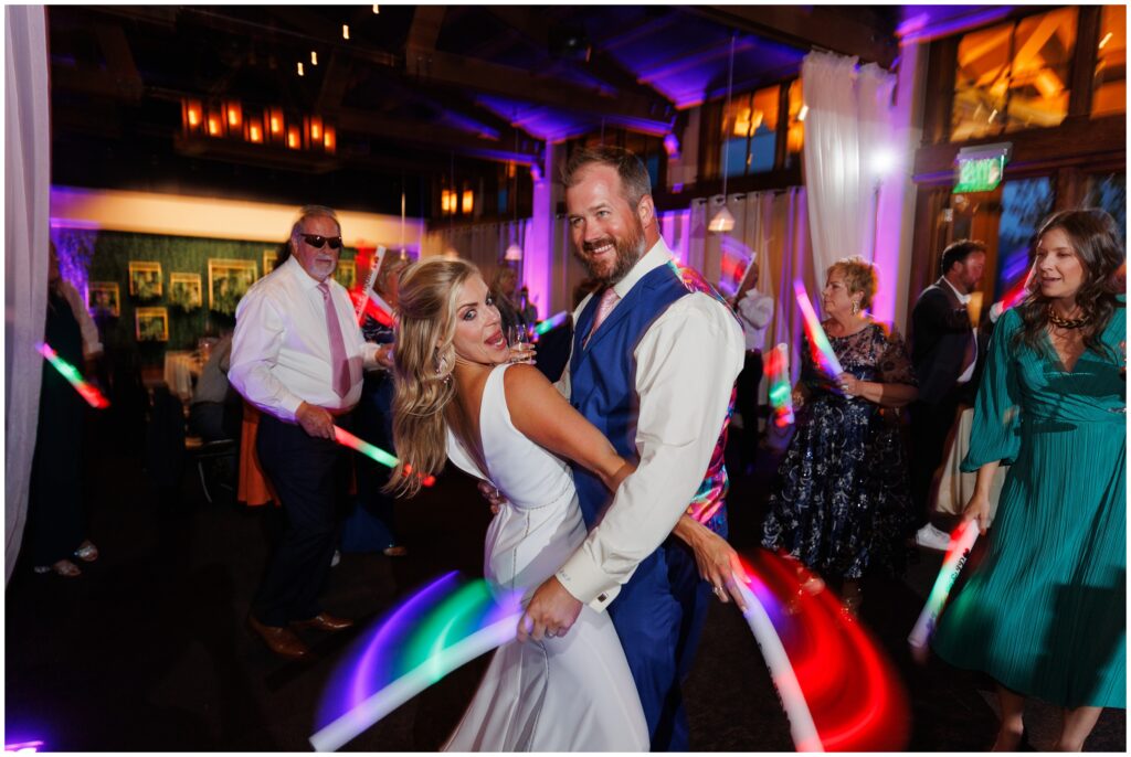 Bride and groom dancing with light sticks during open dancing