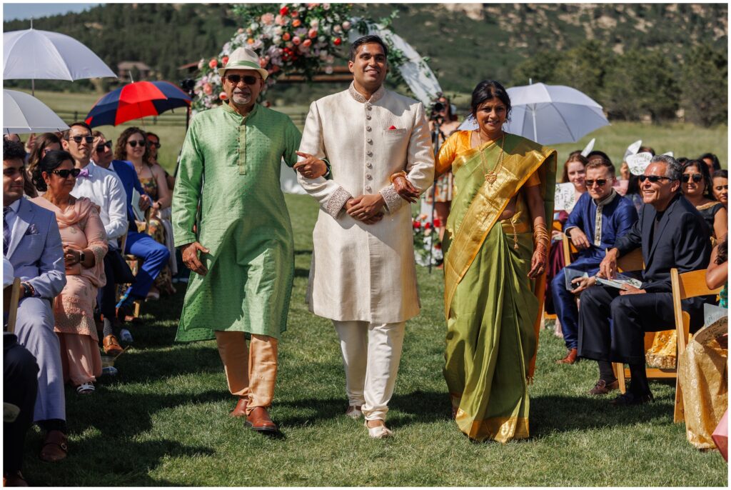 Groom walking down with parents for ceremony at Spruce Mountain 