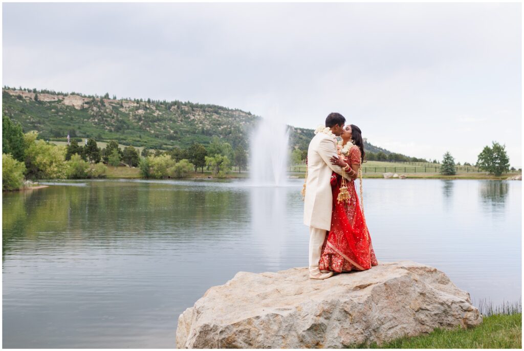 bride and groom standing on a rock with fountain in background