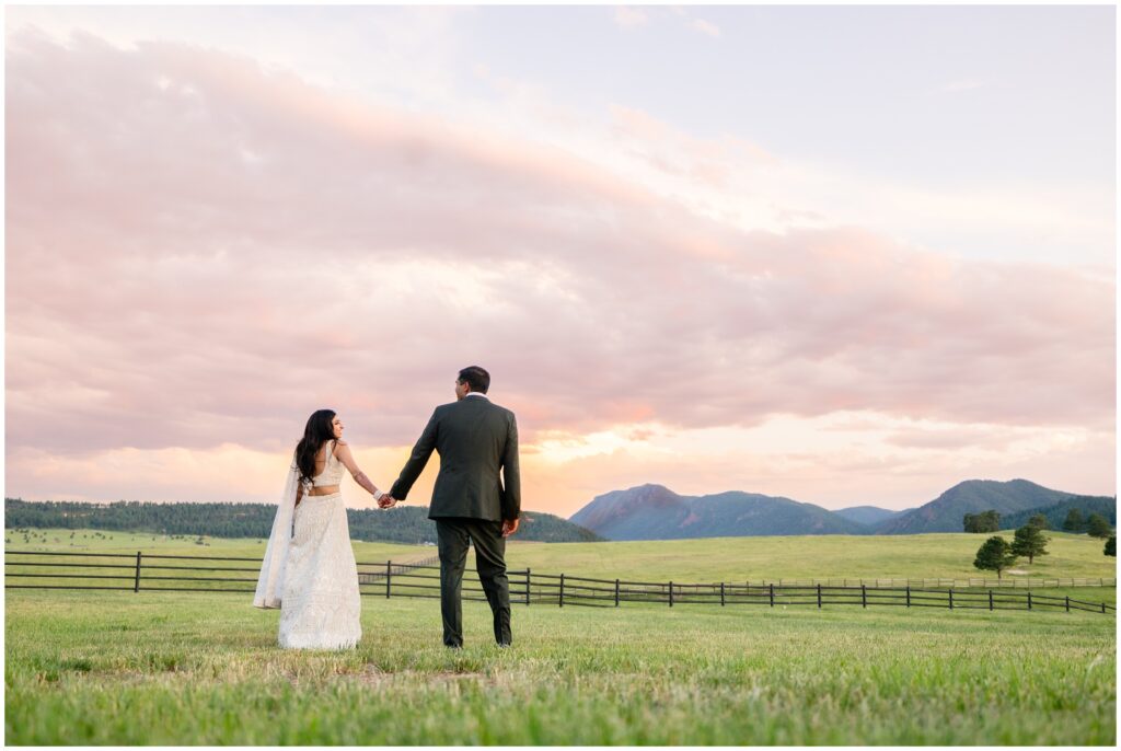bride and groom walking in field at Spruce Mountain