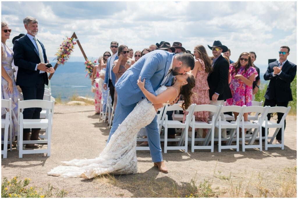 groom dipping bride and kissing her at the end of wedding ceremony at Steamboat mountain