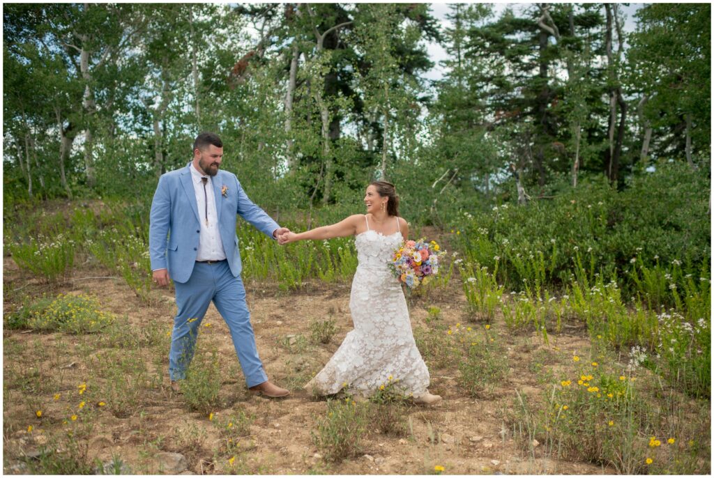 Bride and groom holding hands walking through Steamboat forest