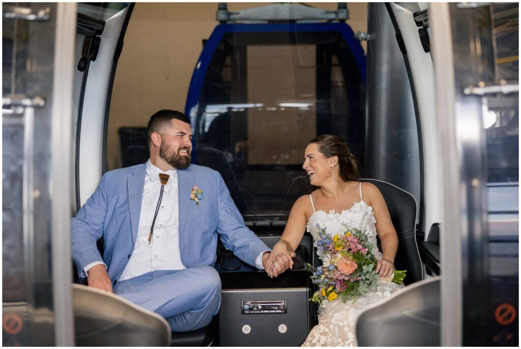 bride holding hands with groom sitting in gondola at Steamboat mountain