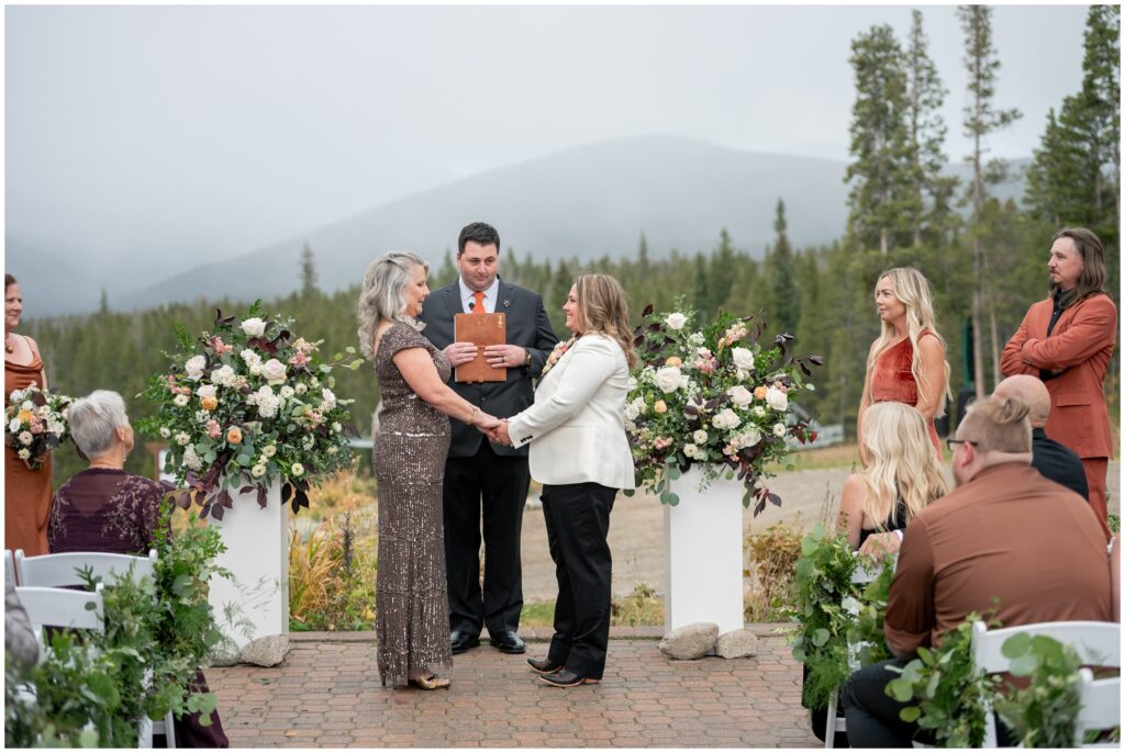 Brides holding hands during ceremony at at ten mile station