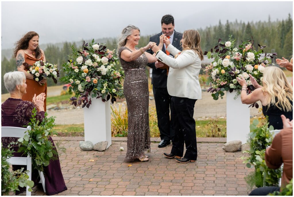 Brides raising and holding hands during wedding ceremony